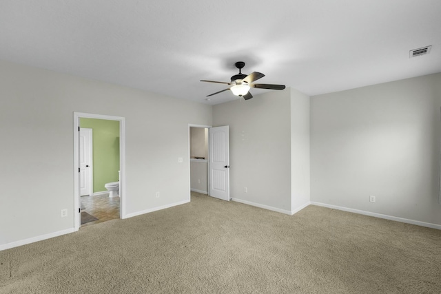 unfurnished bedroom featuring ceiling fan, light colored carpet, and ensuite bath