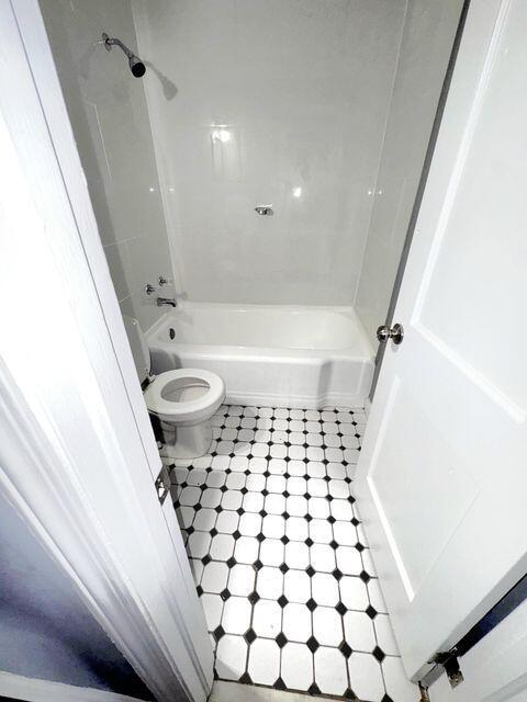 bathroom featuring toilet and tiled shower / bath