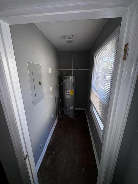 utility room with electric panel and water heater