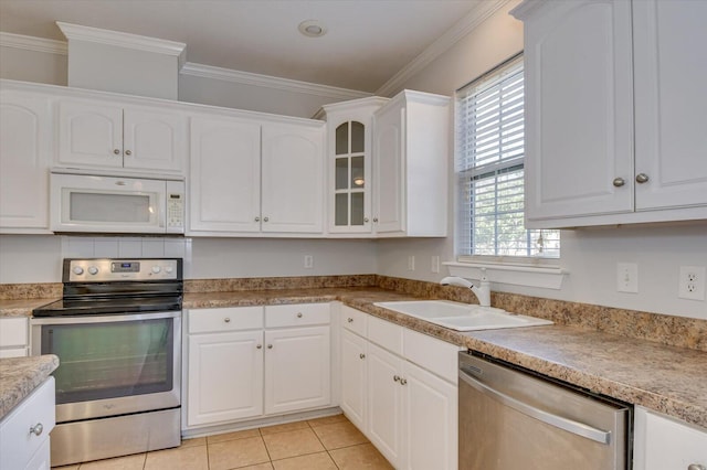 kitchen with light tile patterned floors, sink, stainless steel appliances, and white cabinetry