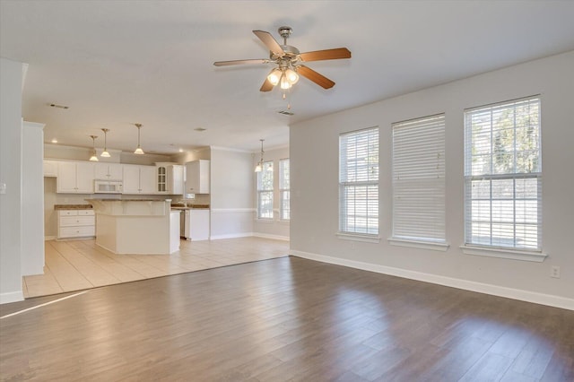 unfurnished living room with ceiling fan and light hardwood / wood-style flooring