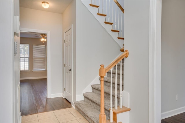 stairway with ceiling fan and tile patterned floors