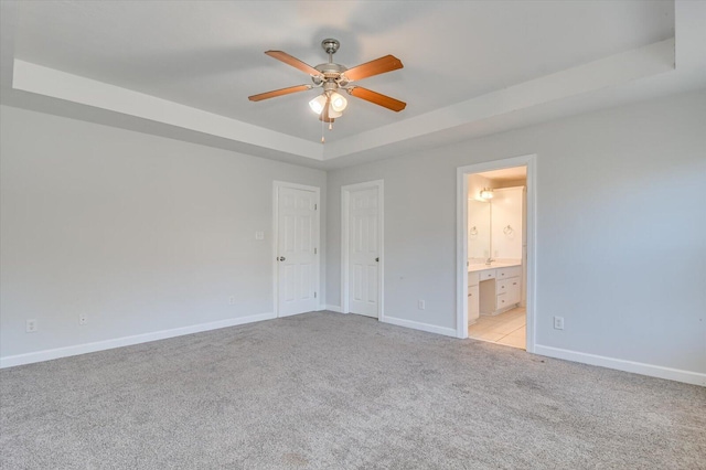 spare room with light carpet, ceiling fan, and a tray ceiling