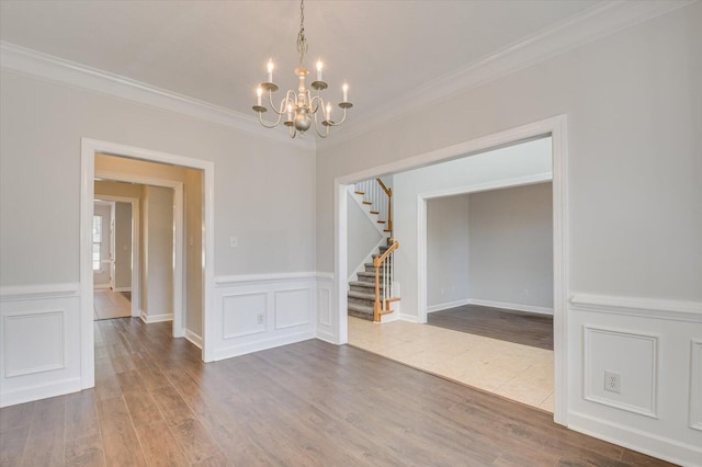 spare room with crown molding, hardwood / wood-style flooring, and a notable chandelier