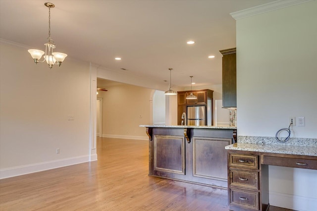 kitchen featuring pendant lighting, stainless steel refrigerator, and ornamental molding