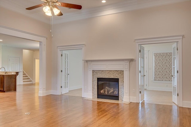 unfurnished living room with ceiling fan, a fireplace, light wood-type flooring, and ornamental molding