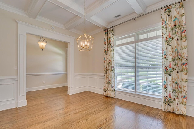 unfurnished dining area featuring beam ceiling, coffered ceiling, light hardwood / wood-style flooring, crown molding, and a chandelier