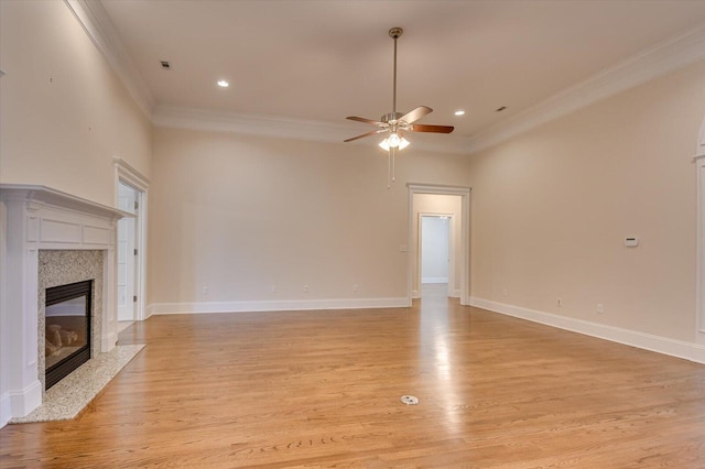 unfurnished living room with a premium fireplace, crown molding, ceiling fan, and light hardwood / wood-style floors