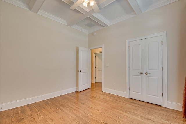 unfurnished bedroom with coffered ceiling, ceiling fan, light hardwood / wood-style flooring, beamed ceiling, and a closet