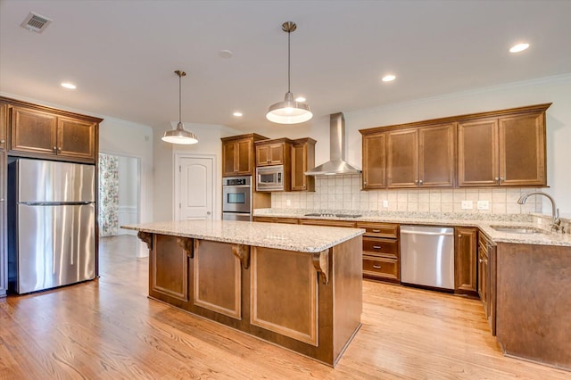 kitchen with sink, wall chimney range hood, backsplash, pendant lighting, and appliances with stainless steel finishes