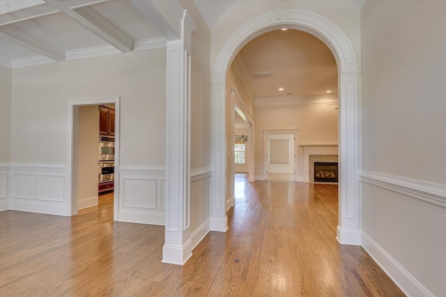 hall with beamed ceiling, light wood-type flooring, and ornamental molding