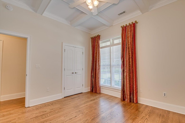 unfurnished bedroom featuring beam ceiling, multiple windows, ceiling fan, and coffered ceiling