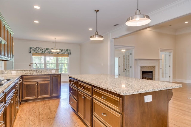 kitchen featuring light stone countertops, a center island, decorative light fixtures, and light hardwood / wood-style flooring