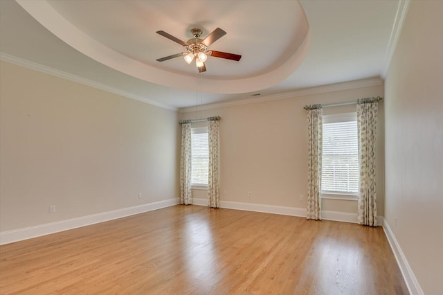 unfurnished room with a tray ceiling, ceiling fan, ornamental molding, and light wood-type flooring