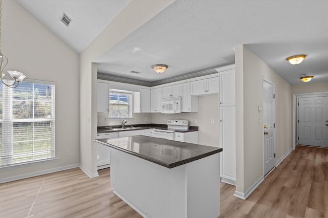 kitchen featuring visible vents, a sink, white appliances, baseboards, and white cabinetry