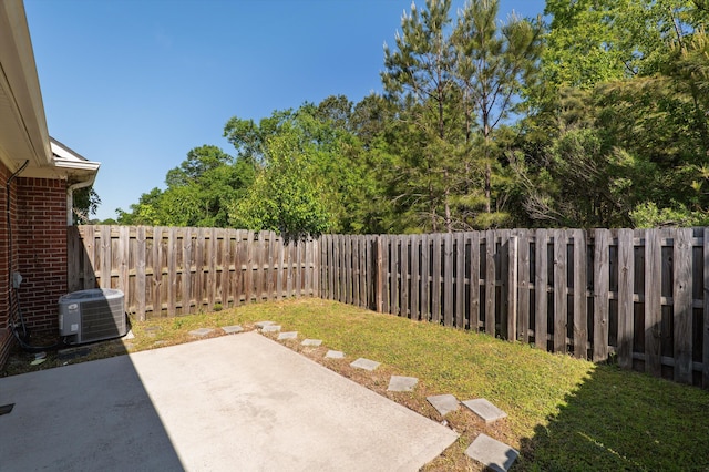 view of yard with a fenced backyard, central AC unit, and a patio
