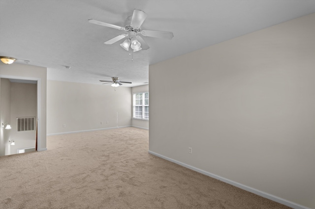 carpeted empty room featuring visible vents, baseboards, and ceiling fan