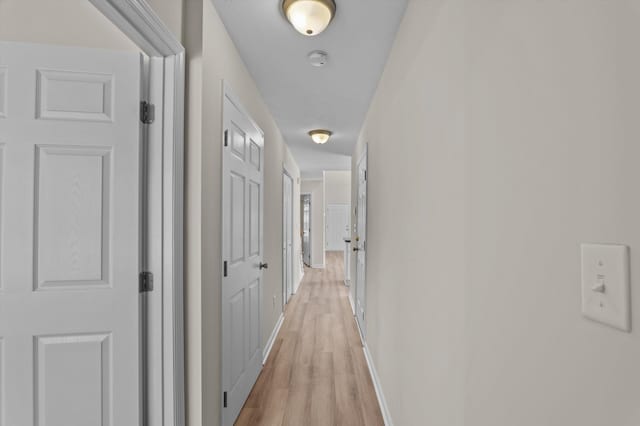 corridor featuring baseboards and light wood-style floors