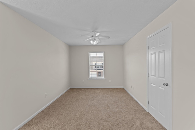 carpeted empty room with a ceiling fan and baseboards