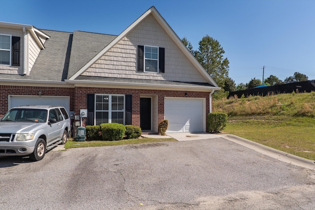 view of front of house with an attached garage, a shingled roof, driveway, and brick siding