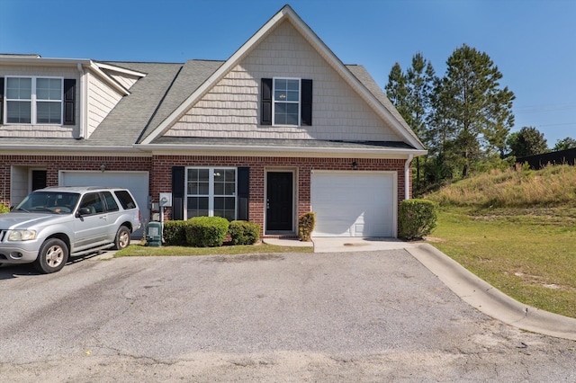 view of front facade featuring an attached garage, driveway, brick siding, and roof with shingles