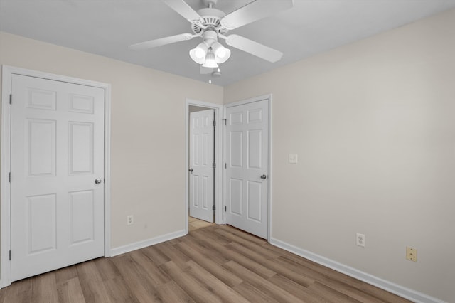 unfurnished bedroom with wood finished floors, baseboards, and a ceiling fan