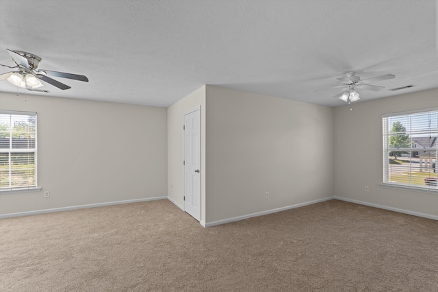 carpeted empty room with visible vents, baseboards, and ceiling fan
