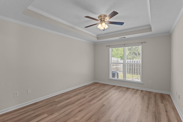 unfurnished room featuring light wood finished floors, a raised ceiling, visible vents, a ceiling fan, and ornamental molding