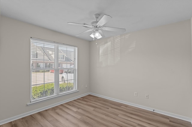 spare room featuring baseboards, a ceiling fan, and light wood-style floors