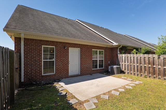 rear view of property featuring brick siding, a yard, a shingled roof, and a patio