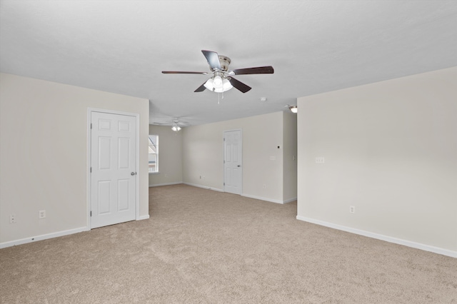 spare room featuring a ceiling fan, baseboards, and light carpet