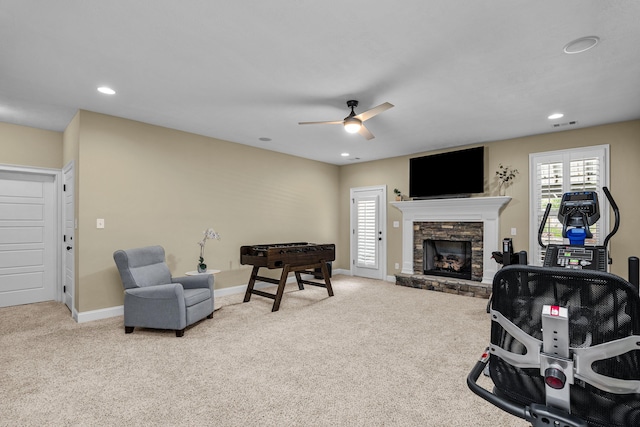 living room with ceiling fan, light colored carpet, and a fireplace