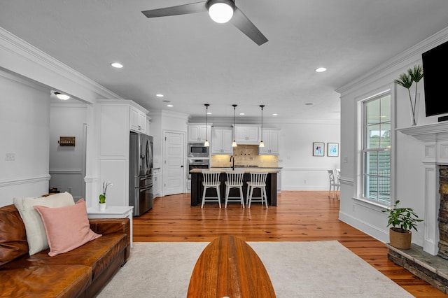 living room with ceiling fan, a stone fireplace, crown molding, and dark hardwood / wood-style floors