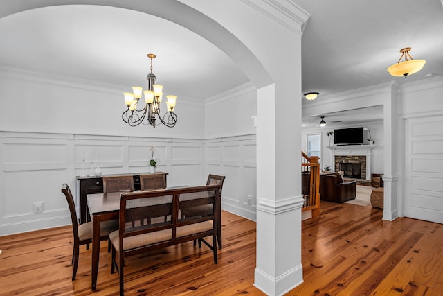 dining area with a fireplace, a chandelier, crown molding, and wood-type flooring