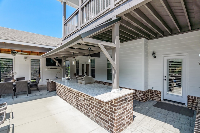 view of patio with a bar, ceiling fan, a balcony, and area for grilling