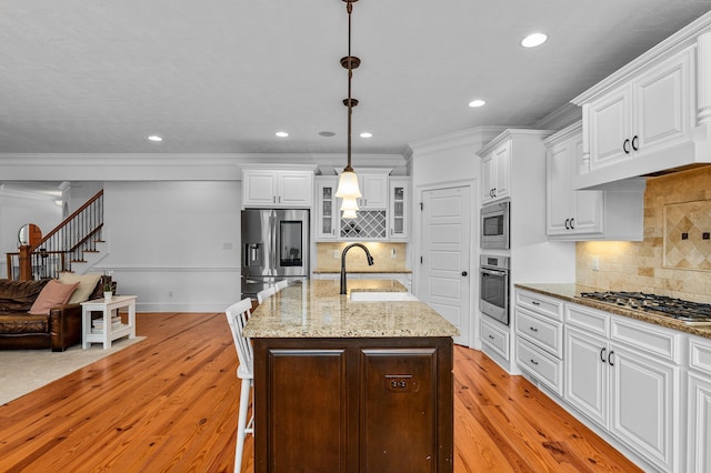 kitchen featuring sink, light wood-type flooring, pendant lighting, and appliances with stainless steel finishes