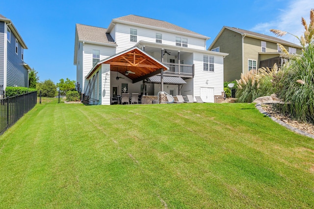 back of house with ceiling fan, a balcony, and a lawn