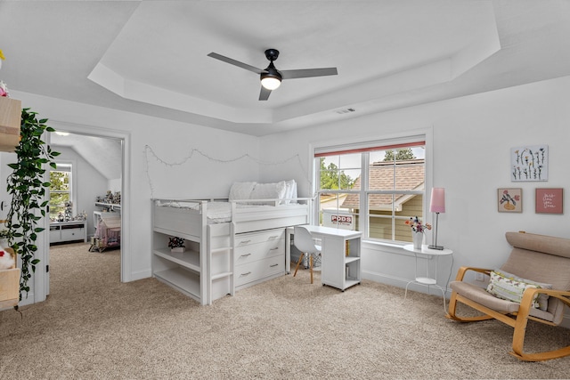 bedroom featuring a raised ceiling, light carpet, and ceiling fan