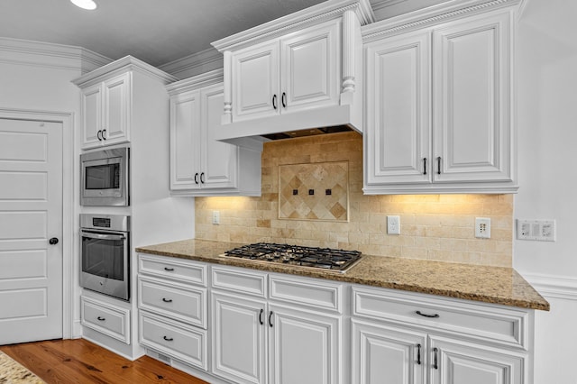 kitchen with stainless steel appliances, ornamental molding, and white cabinets