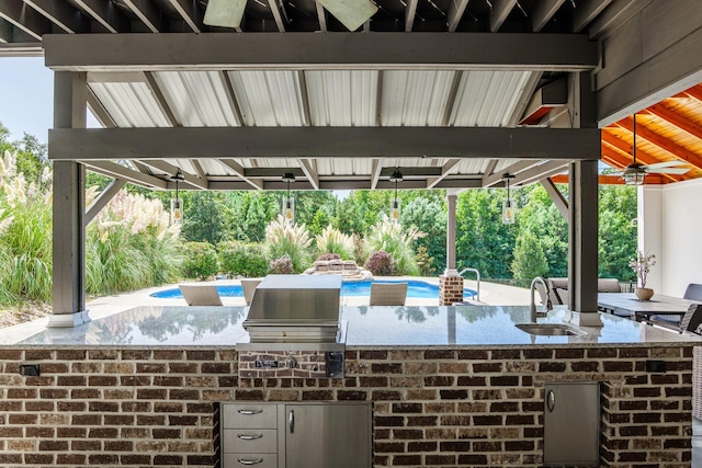 view of patio / terrace featuring ceiling fan, a grill, an outdoor kitchen, and a wet bar