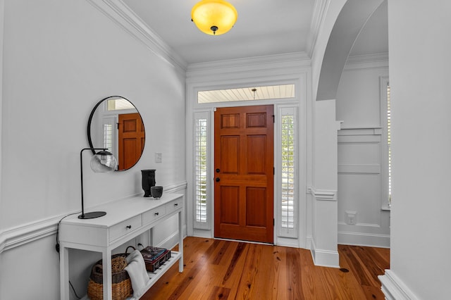 foyer entrance with crown molding and hardwood / wood-style flooring