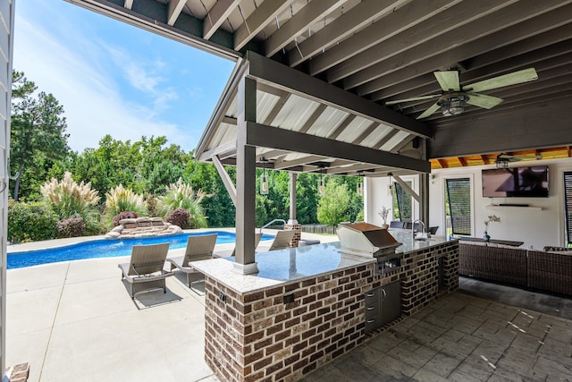 view of patio with an outdoor kitchen, a bar, ceiling fan, and area for grilling