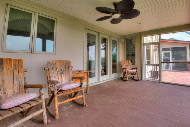 sunroom with a wooden deck, ceiling fan, wood finished floors, and crown molding