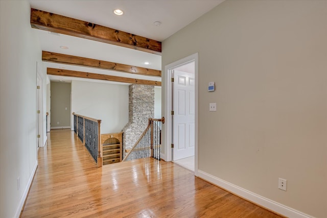 unfurnished room with light wood-style floors, baseboards, recessed lighting, and beam ceiling