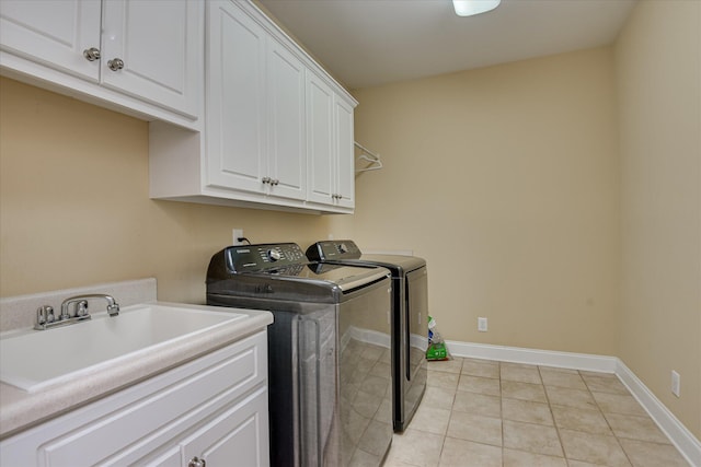 clothes washing area featuring independent washer and dryer, cabinet space, light tile patterned floors, and baseboards
