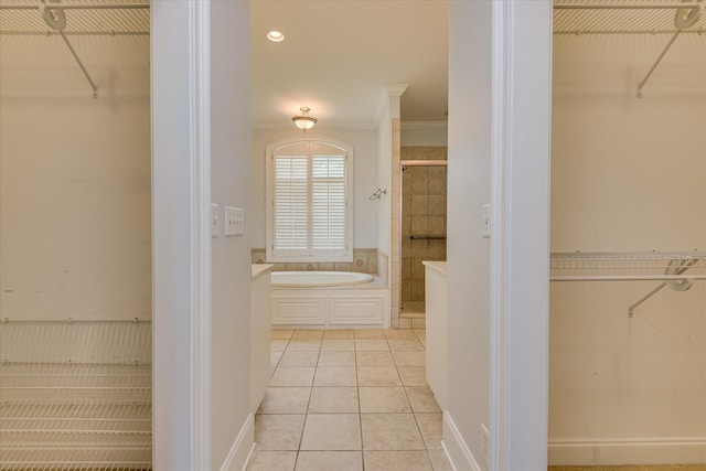 full bath featuring a spacious closet, a shower stall, a garden tub, tile patterned flooring, and ornamental molding