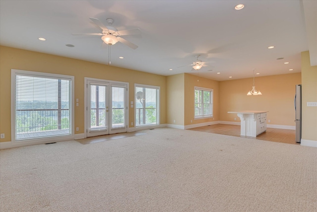 unfurnished living room featuring ceiling fan, light carpet, baseboards, recessed lighting, and a chandelier