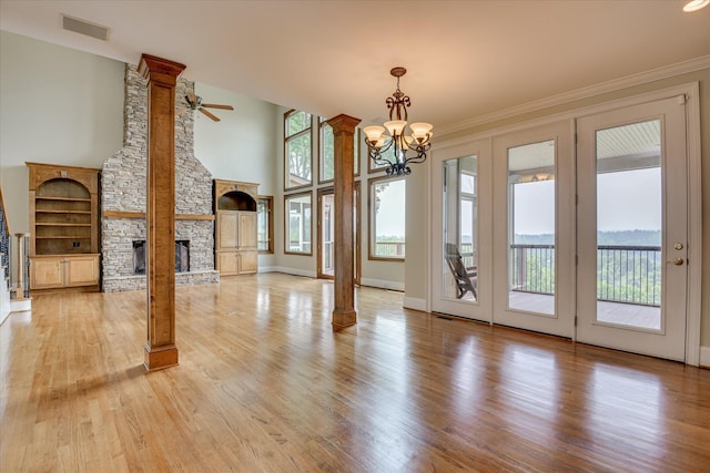 unfurnished living room with light wood-type flooring, a chandelier, a ceiling fan, a fireplace, and baseboards