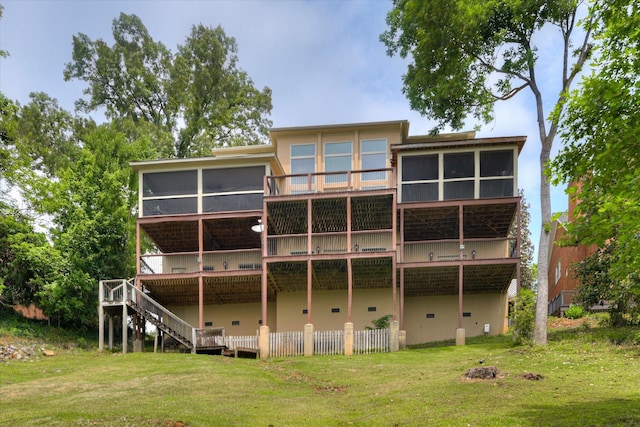 back of house featuring a sunroom, stairway, a wooden deck, and a yard