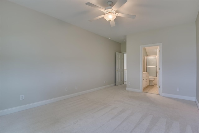 unfurnished bedroom featuring light colored carpet, baseboards, ensuite bathroom, and ceiling fan